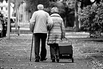 Elderly couple walking together on a park path in black and white