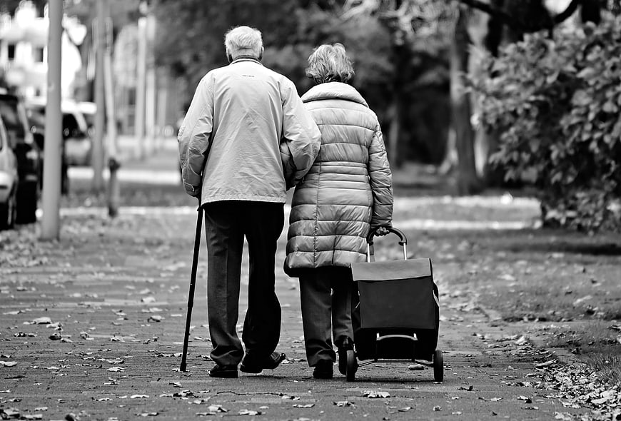 Elderly couple walking together on a park path in black and white