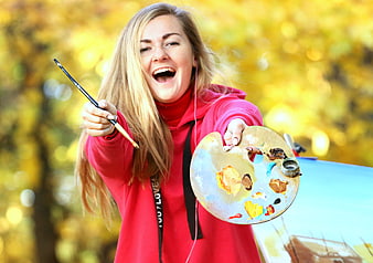 Joyful young female artist painting outdoors in autumn