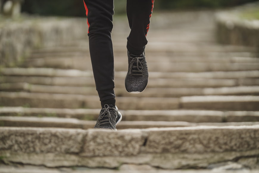 Runner's legs and feet ascending stone stairs