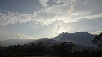 Sun rays breaking through clouds over mountain landscape