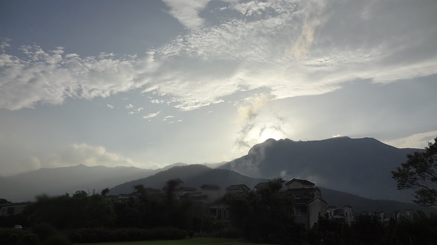 Sun rays breaking through clouds over mountain landscape