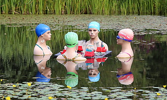 Four Mannequins Wearing Swim Caps Seated at Table in Pond