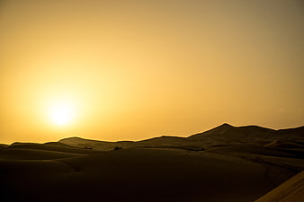 Golden sunset over vast desert sand dunes landscape