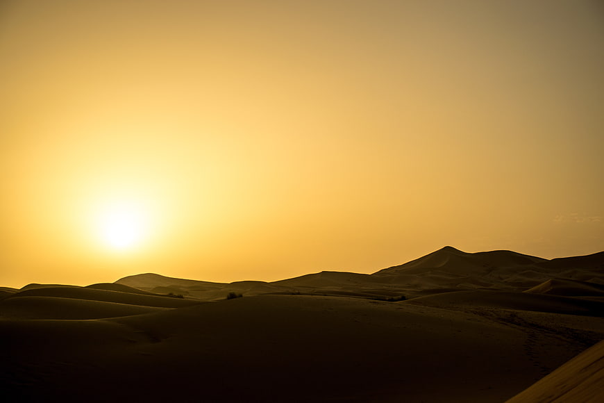Golden sunset over vast desert sand dunes landscape