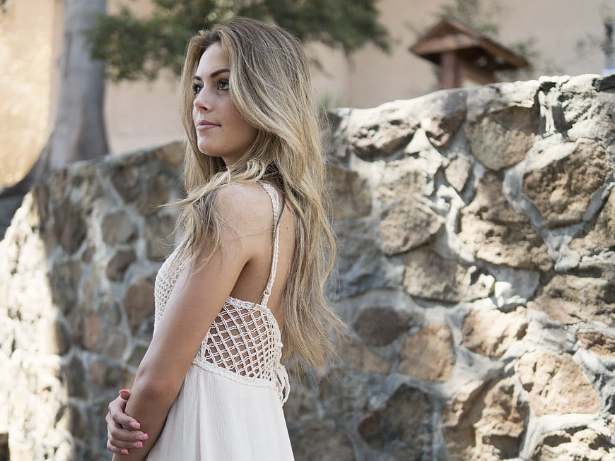 Blonde Woman in White Crochet Dress by Stone Wall