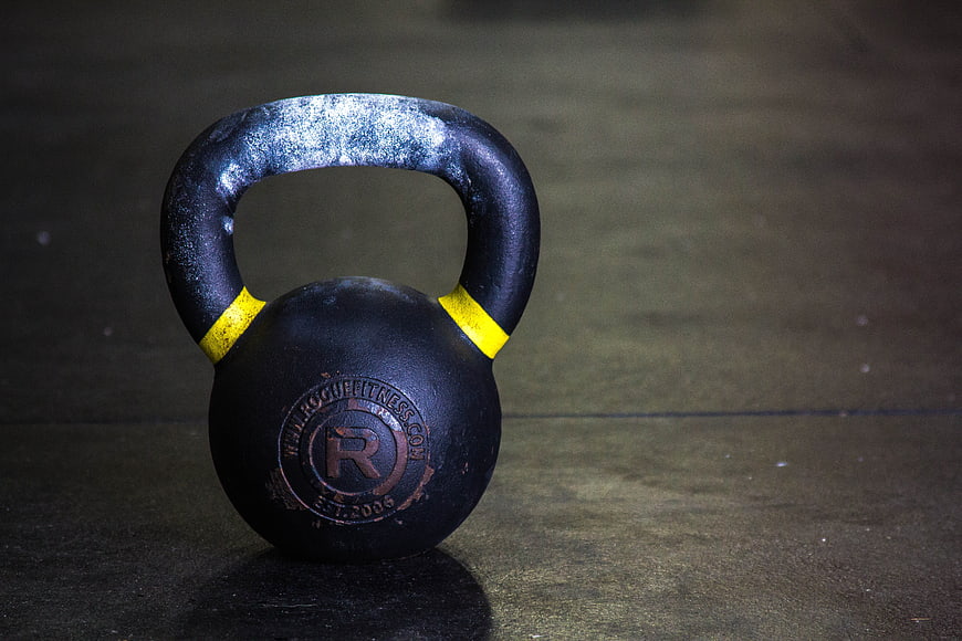 Black Kettlebell with Yellow Accents on Gym Floor