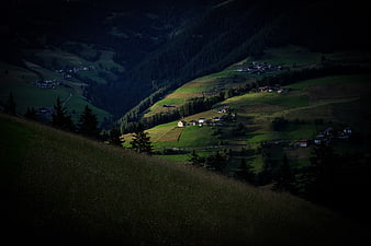 Alpine valley village with dramatic lighting and green hills