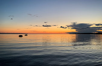 Serene Sunset Over Calm Sea with Distant Wind Turbines
