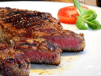 Close-up of juicy grilled steak with tomato and basil