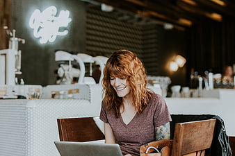Happy woman with red hair working on laptop in cafe
