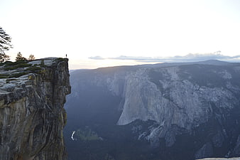 Hiker standing on cliff edge overlooking Yosemite Valley