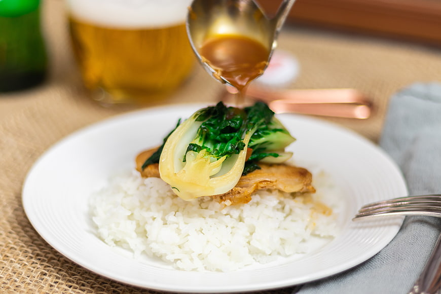 Sauce being poured over rice and bok choy dish