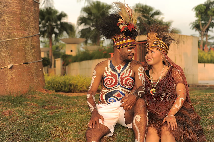 Couple in Traditional Polynesian Tribal Attire Sitting on Grass