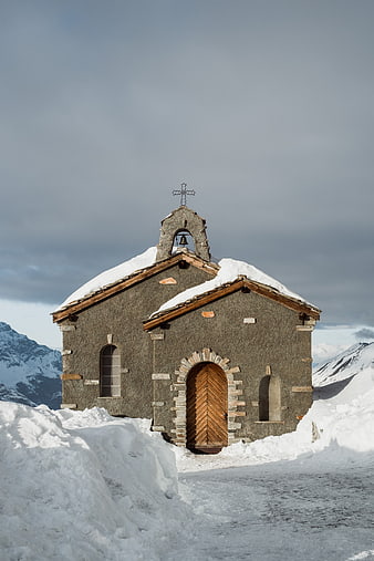 Small stone chapel in snowy mountain landscape