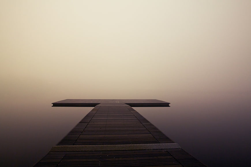 Minimalist wooden pier disappearing into thick fog