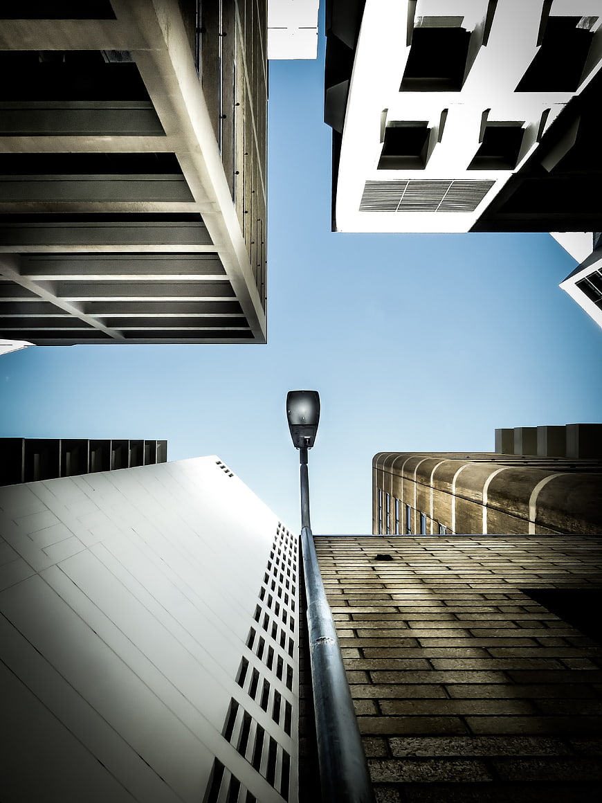 Low angle view of modern architecture and street lamp against blue sky