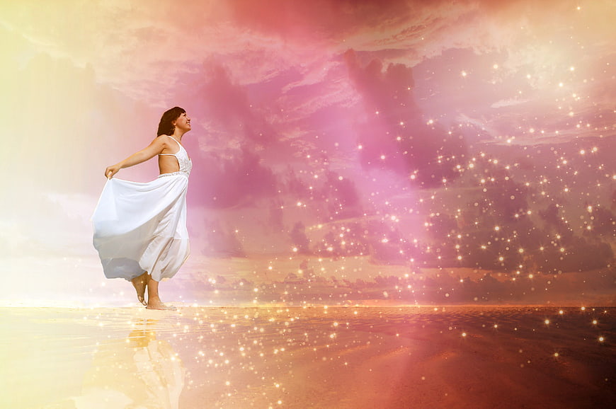 Woman in white dress on magical beach with sparkles