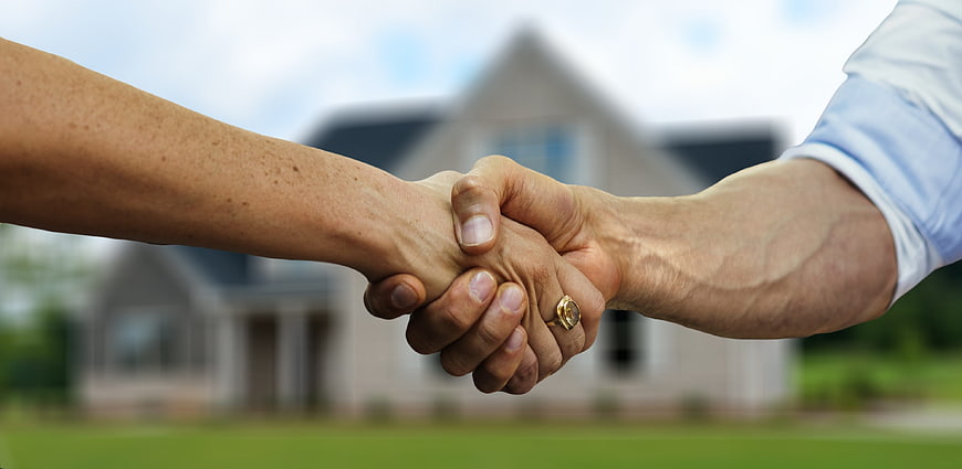 Handshake in front of blurred house background