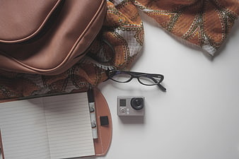 Flat lay of travel accessories, camera, and notebook on white background