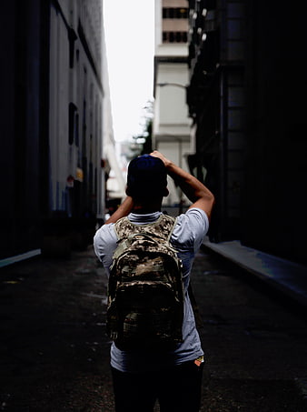 Man with backpack in dark urban alley