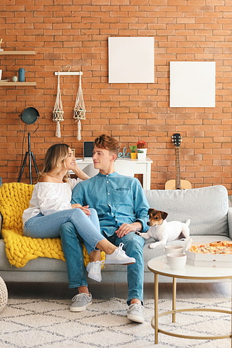 Happy couple relaxing on sofa with dog and pizza