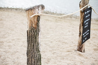 Weathered wooden post with rope on sandy beach