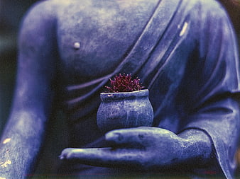Blue Buddha statue holding a small red plant in a clay pot