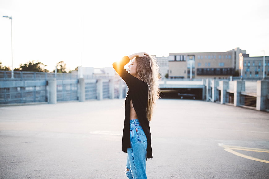 Blonde Woman in Jeans and Black Cardigan on Parking Garage