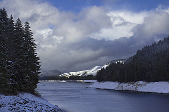 Snowy River Landscape with Pine Forest and Cloudy Sky