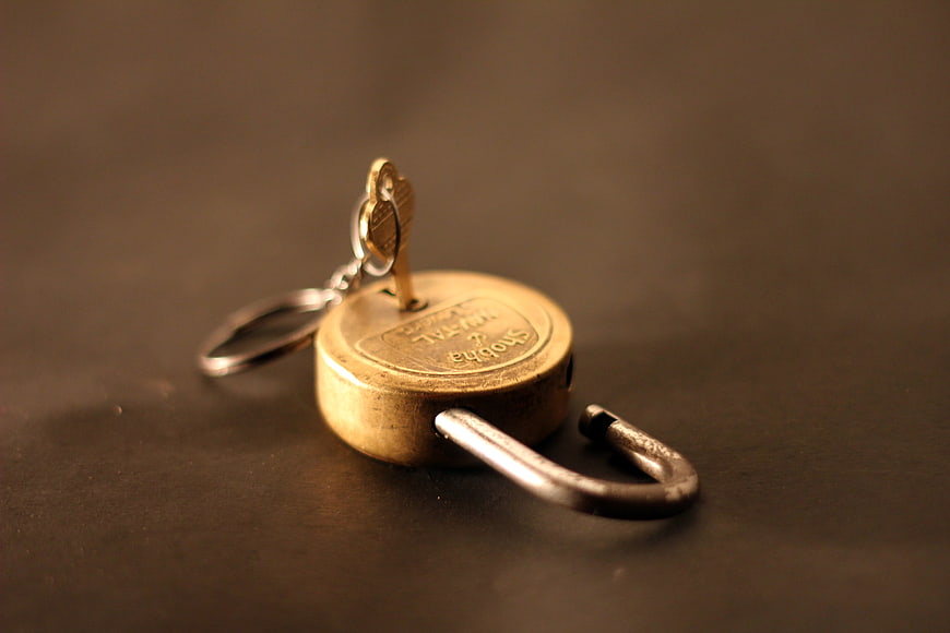 Unlocked Brass Padlock With Key On Dark Surface