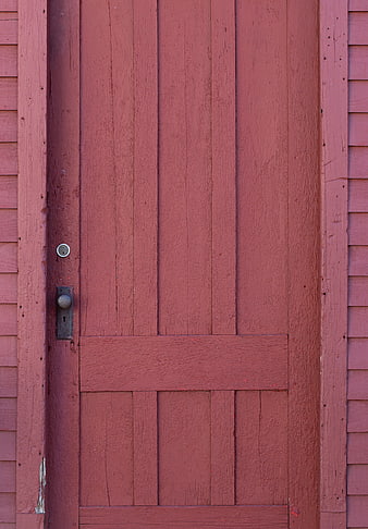 Close-up of a rustic red wooden barn door