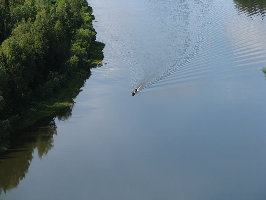 Aerial View of Small Boat on Calm River with Forest Bank