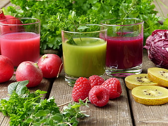 Fresh vegetable and fruit smoothies with herbs, radishes, and kiwi on rustic wood