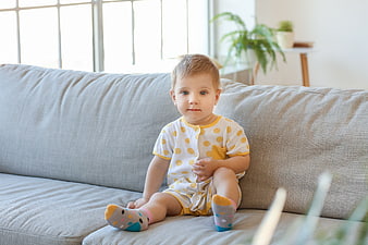 Cute Toddler Boy Sitting on Sofa in Living Room
