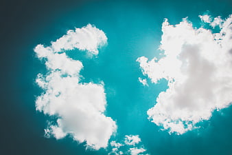 White clouds against a vibrant teal blue sky background