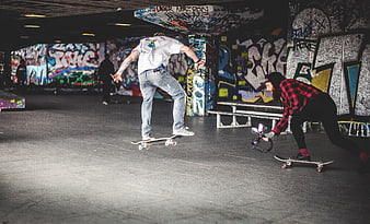Skateboarder filming trick in graffiti skatepark
