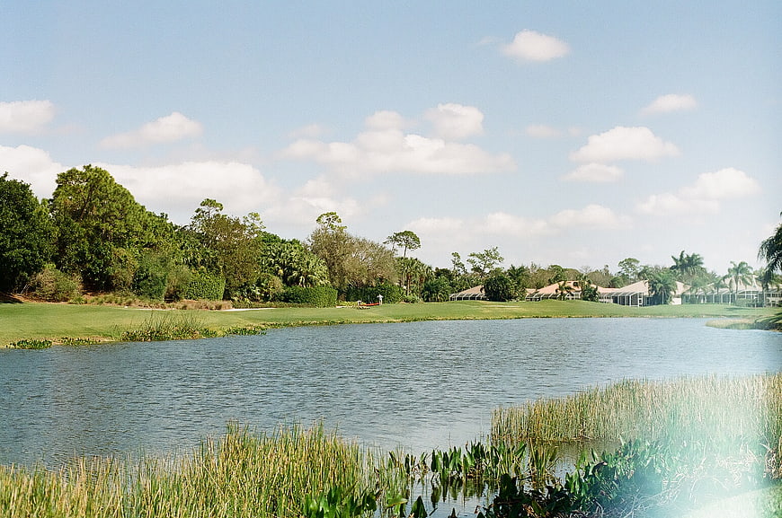 Serene golf course lake with lush green fairways and blue sky