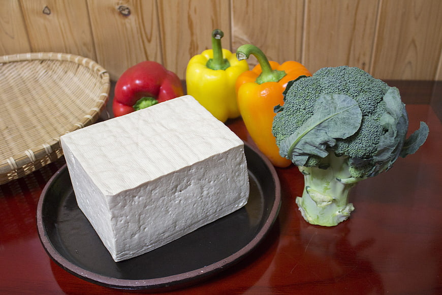 Block of white tofu with colorful bell peppers and broccoli