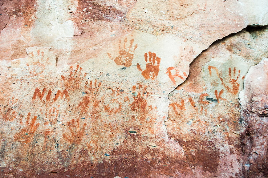 Red handprints and graffiti on weathered stone wall