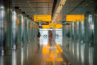 Modern airport terminal hallway with yellow signage and reflections