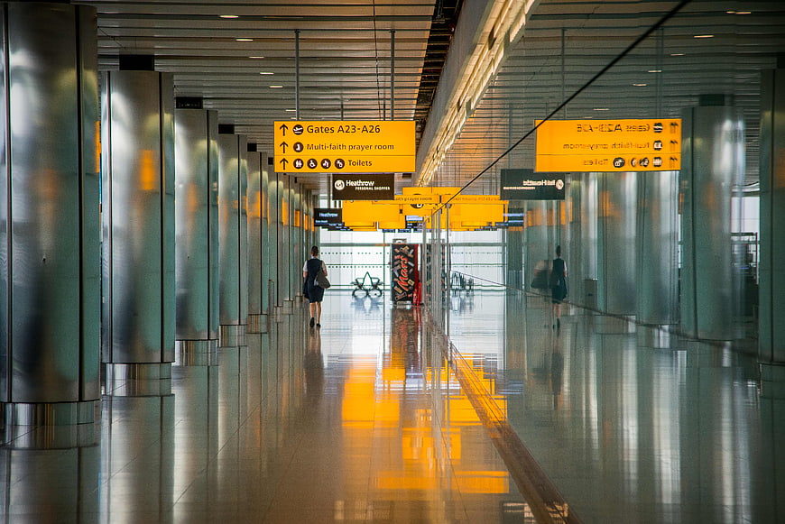 Modern airport terminal hallway with yellow signage and reflections