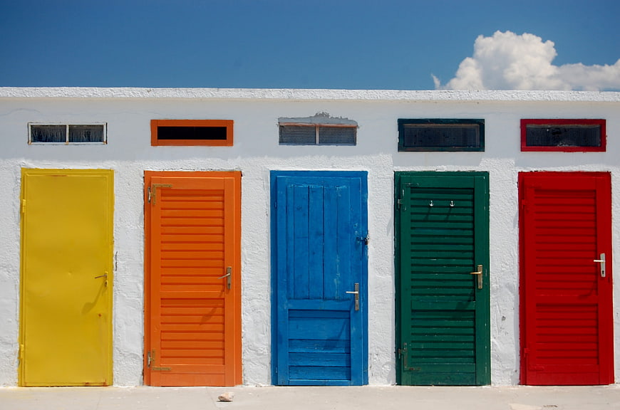 Colorful Doors on White Wall Under Blue Sky