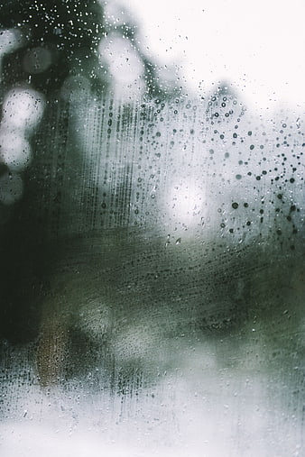 Raindrops on a foggy window with blurred background