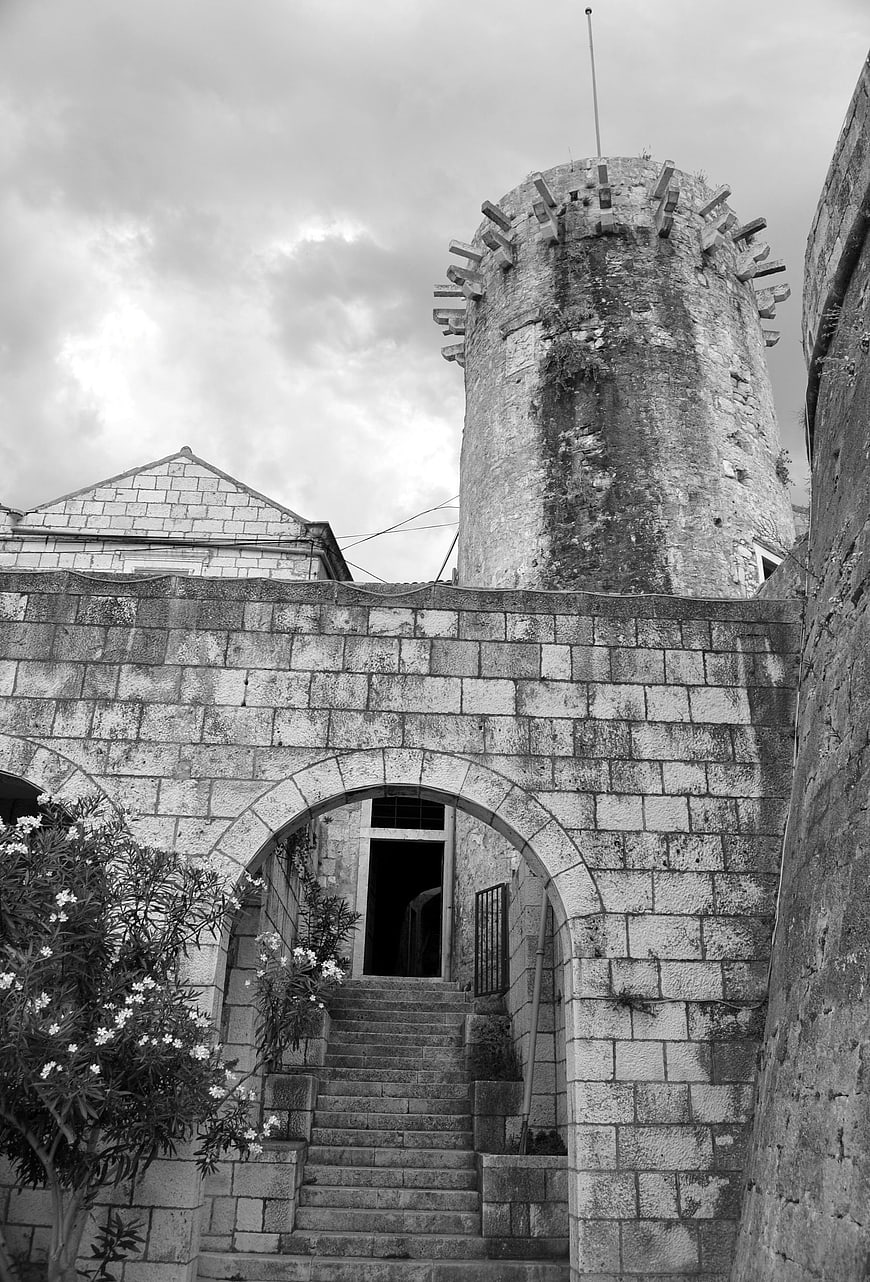 Black and white photo of ancient stone castle tower and archway