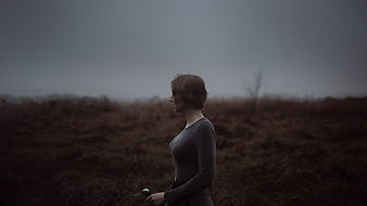 Woman with sword in misty moor landscape