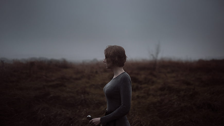 Woman with sword in misty moor landscape