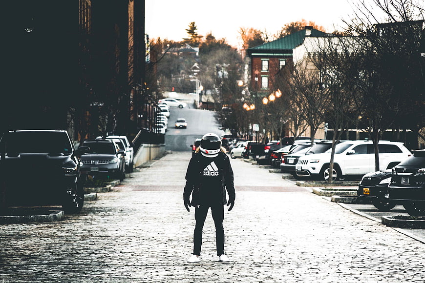 Person in Helmet Standing on Cobblestone Street