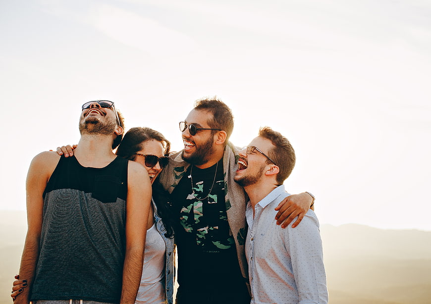 Happy Friends Laughing Together Outdoors at Sunset