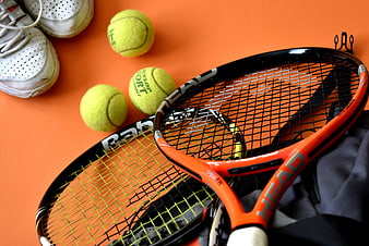 Tennis Equipment Flat Lay with Rackets, Balls, and Shoes on Orange Background